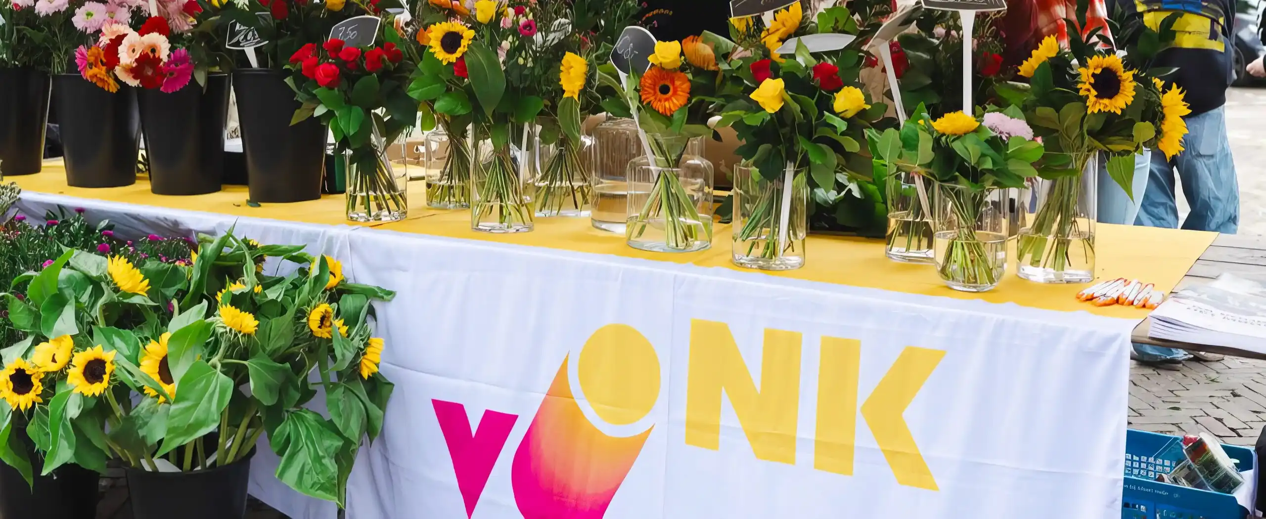 De vlag van Vonk aan een tafel waar vazen met bosjes bloemen op staan, voornamelijk zonnebloemen